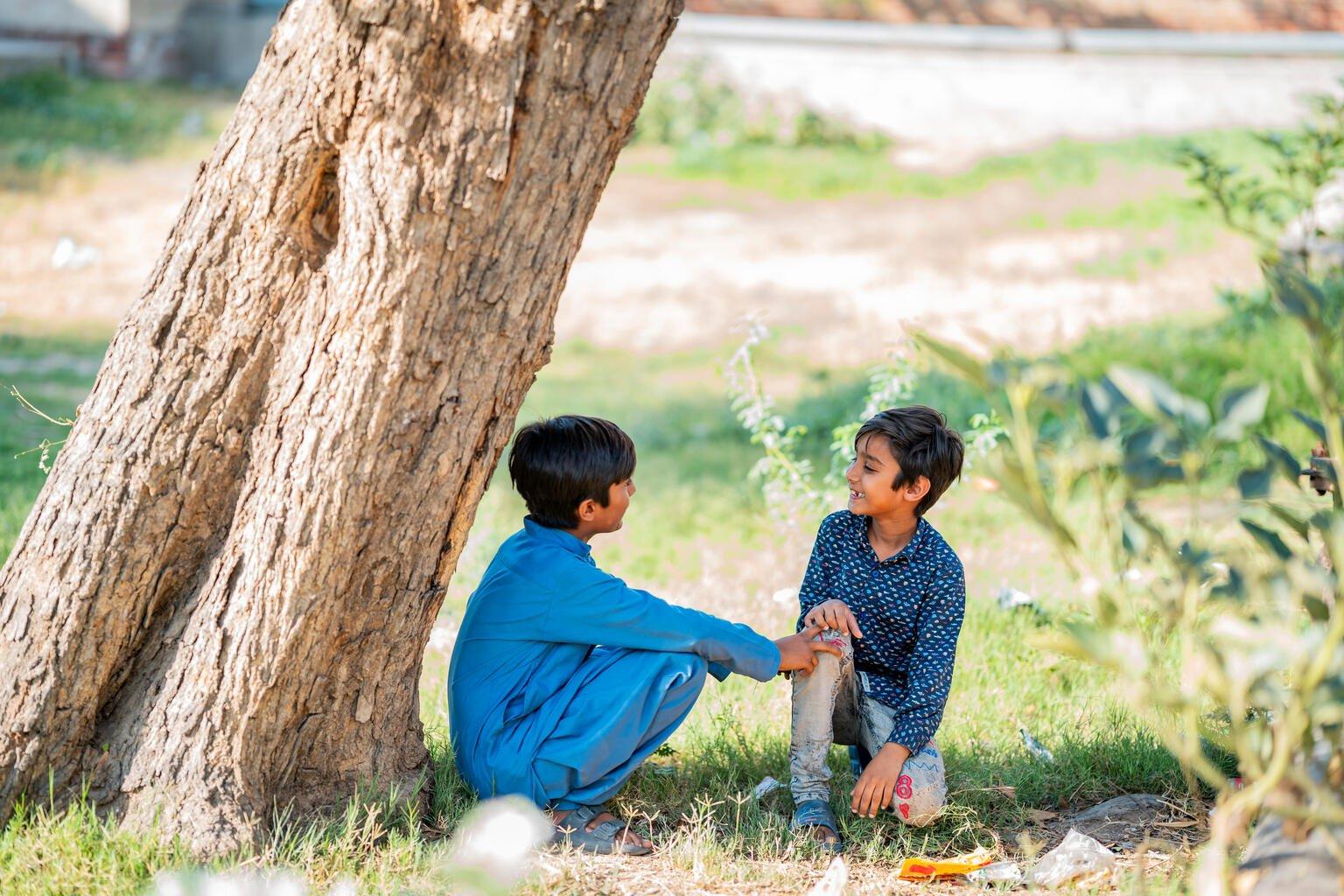 Twee jongens zitten onder een boom in de schaduw in Pakistan tijdens een hittegolf.