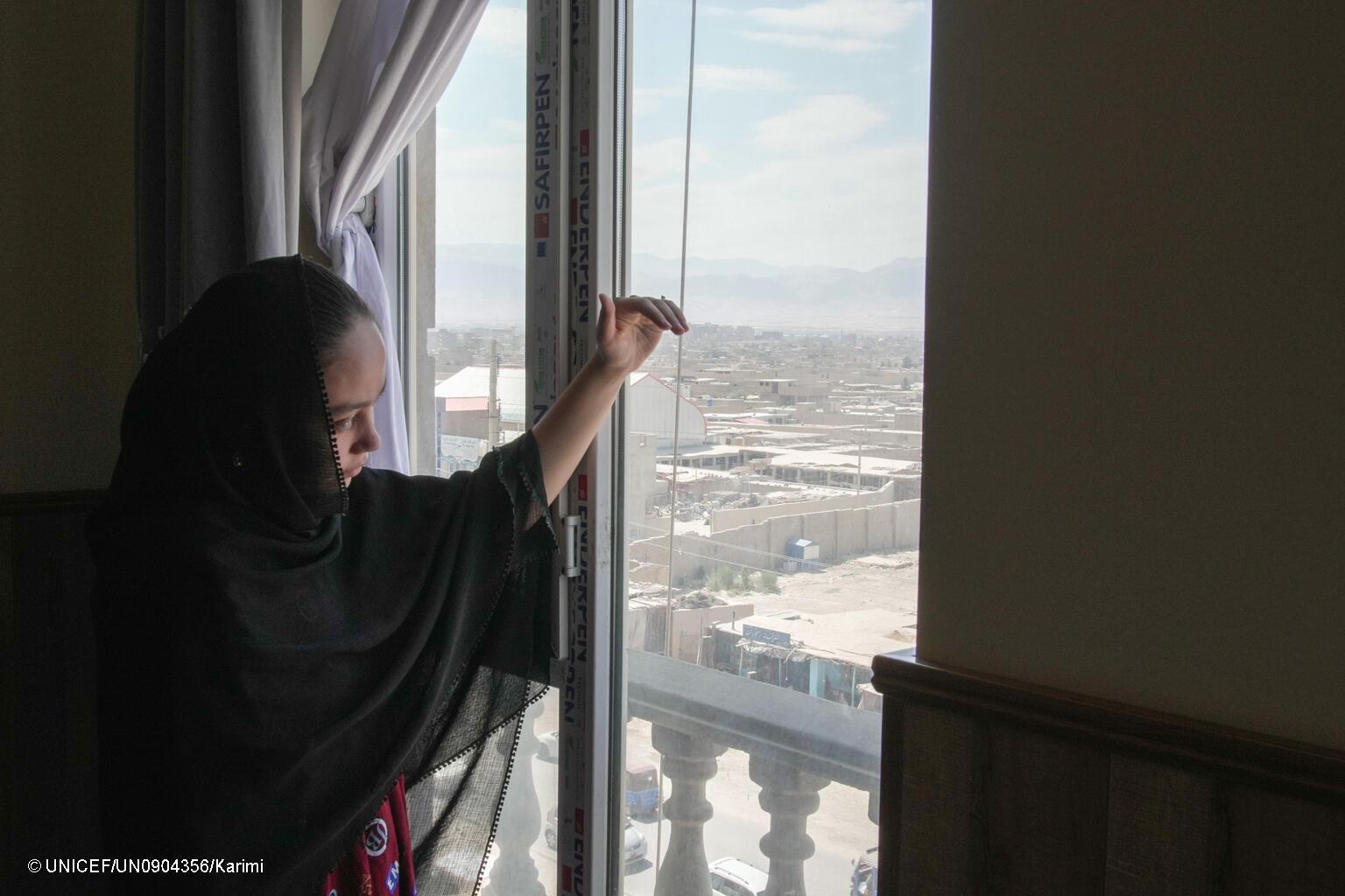 meisje kijkt uit raam in Afghanistan