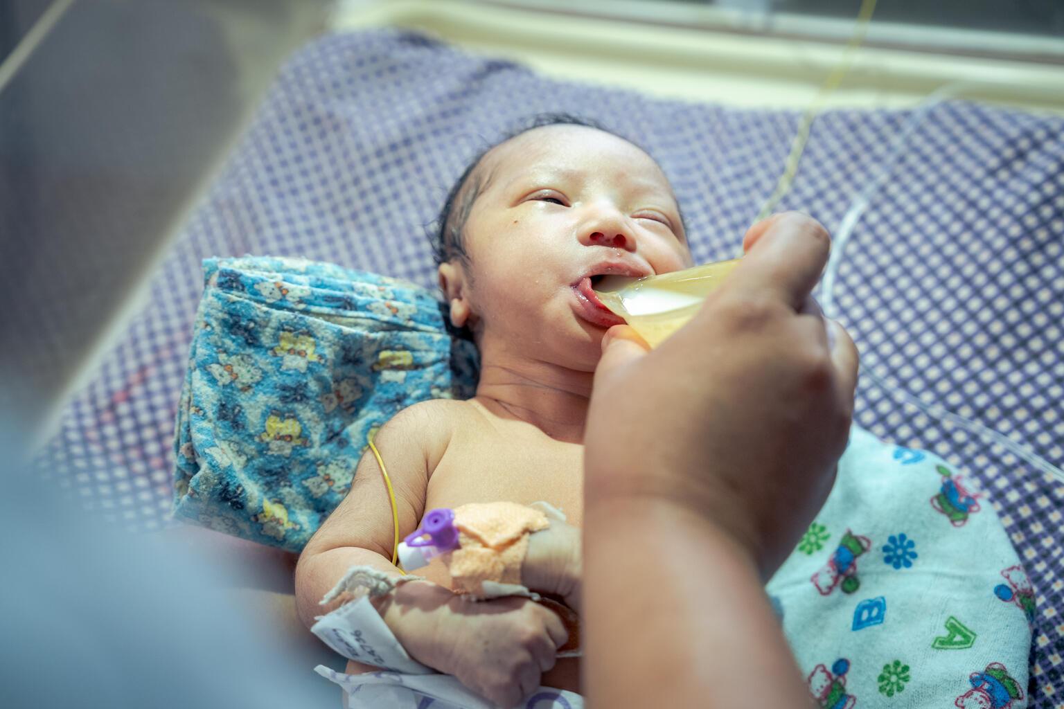 Een baby in Nepal krijgt gedoneerde moedermelk.