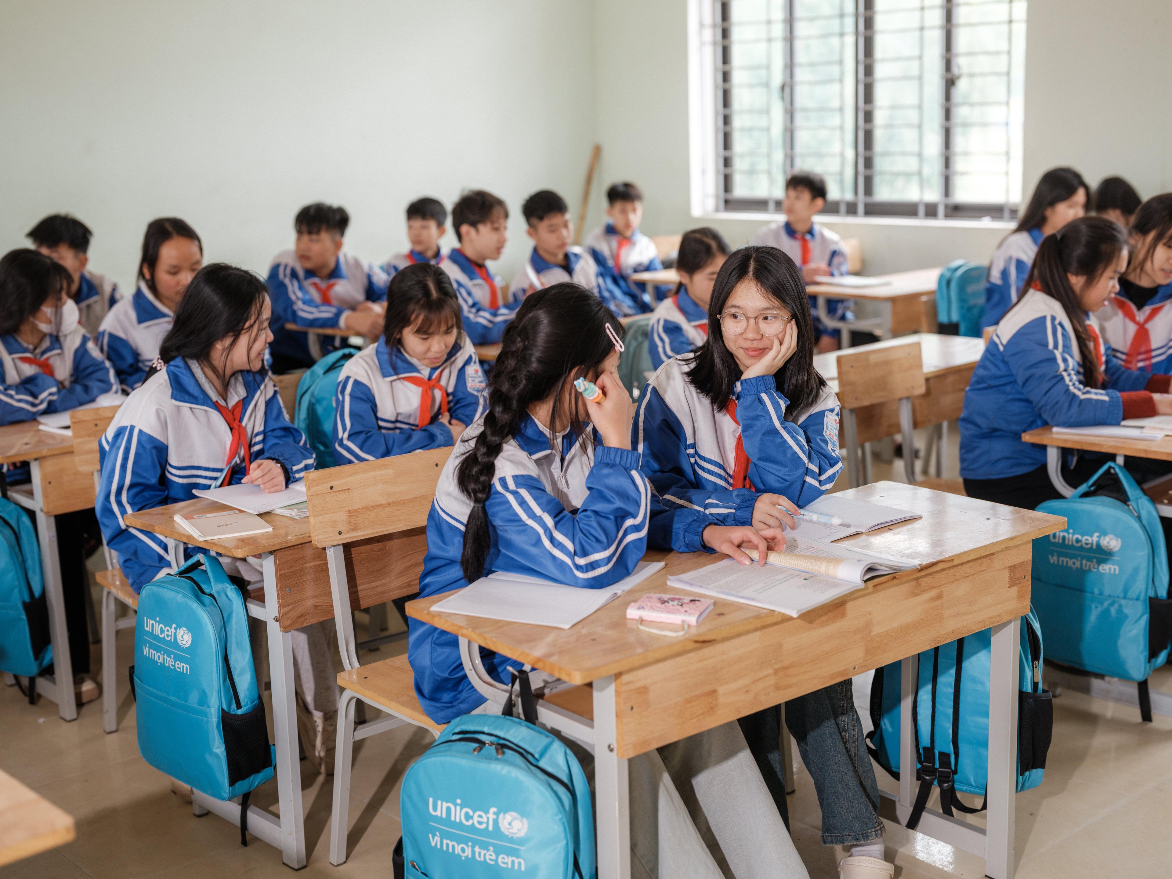 Twee meisjes kijken elkaar aan in een vol klaslokaal in Vietnam