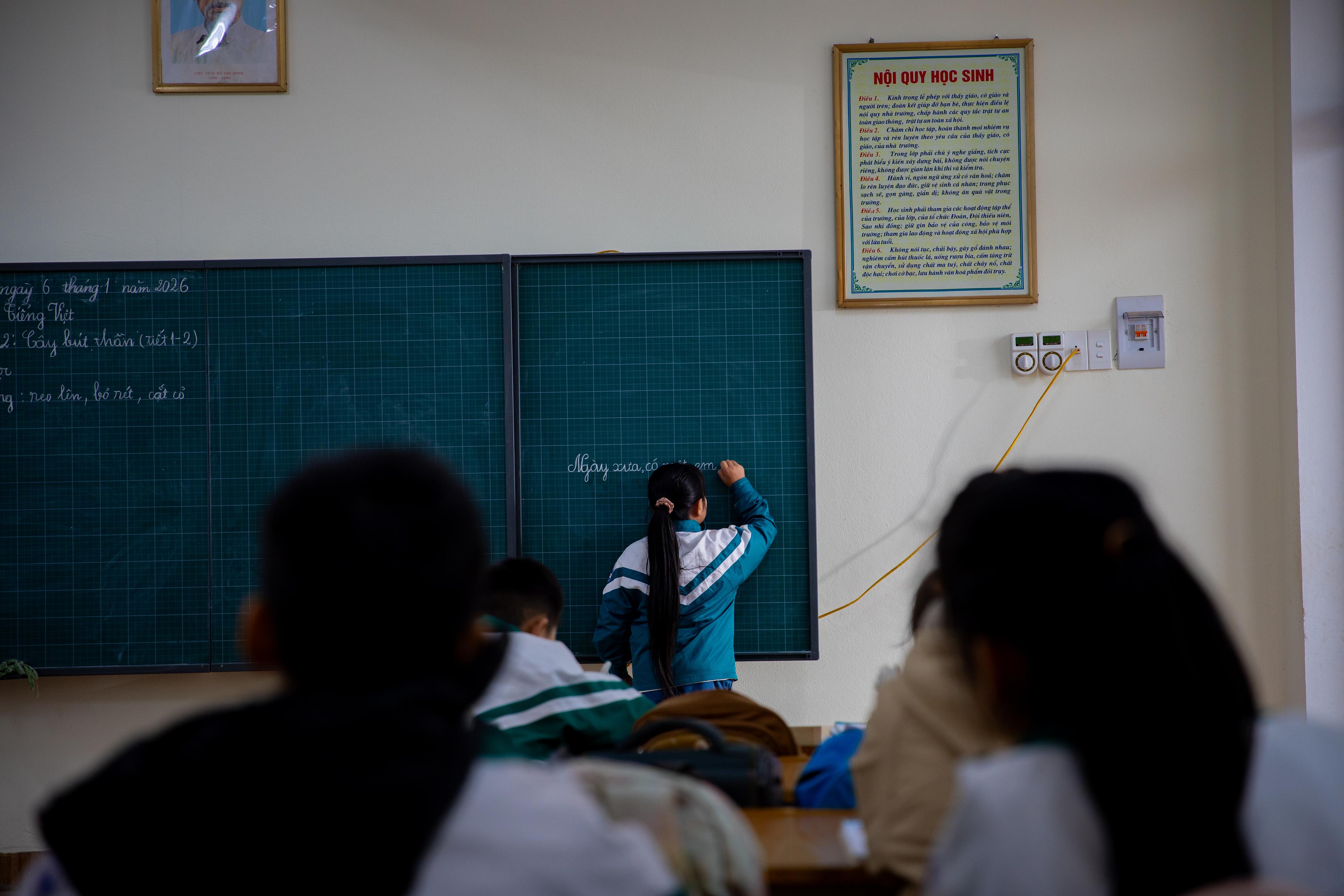 Meisje schrijft op krijtbord in klaslokaal in Vietnam