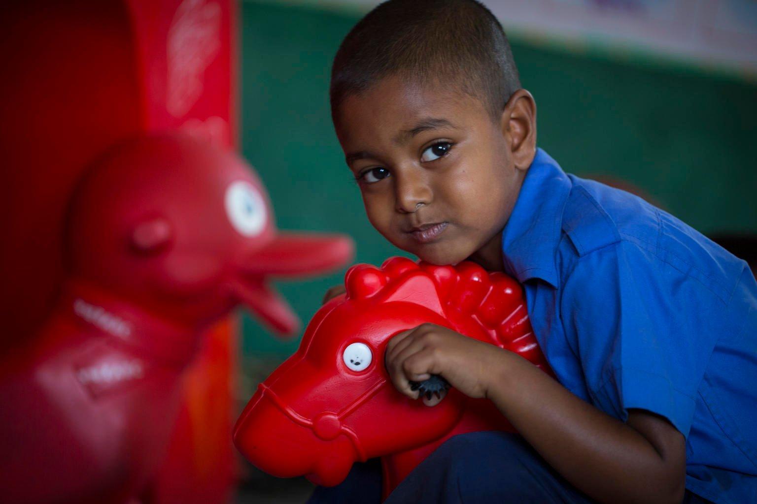 Kind op speelgoedpaard in Bangladesh