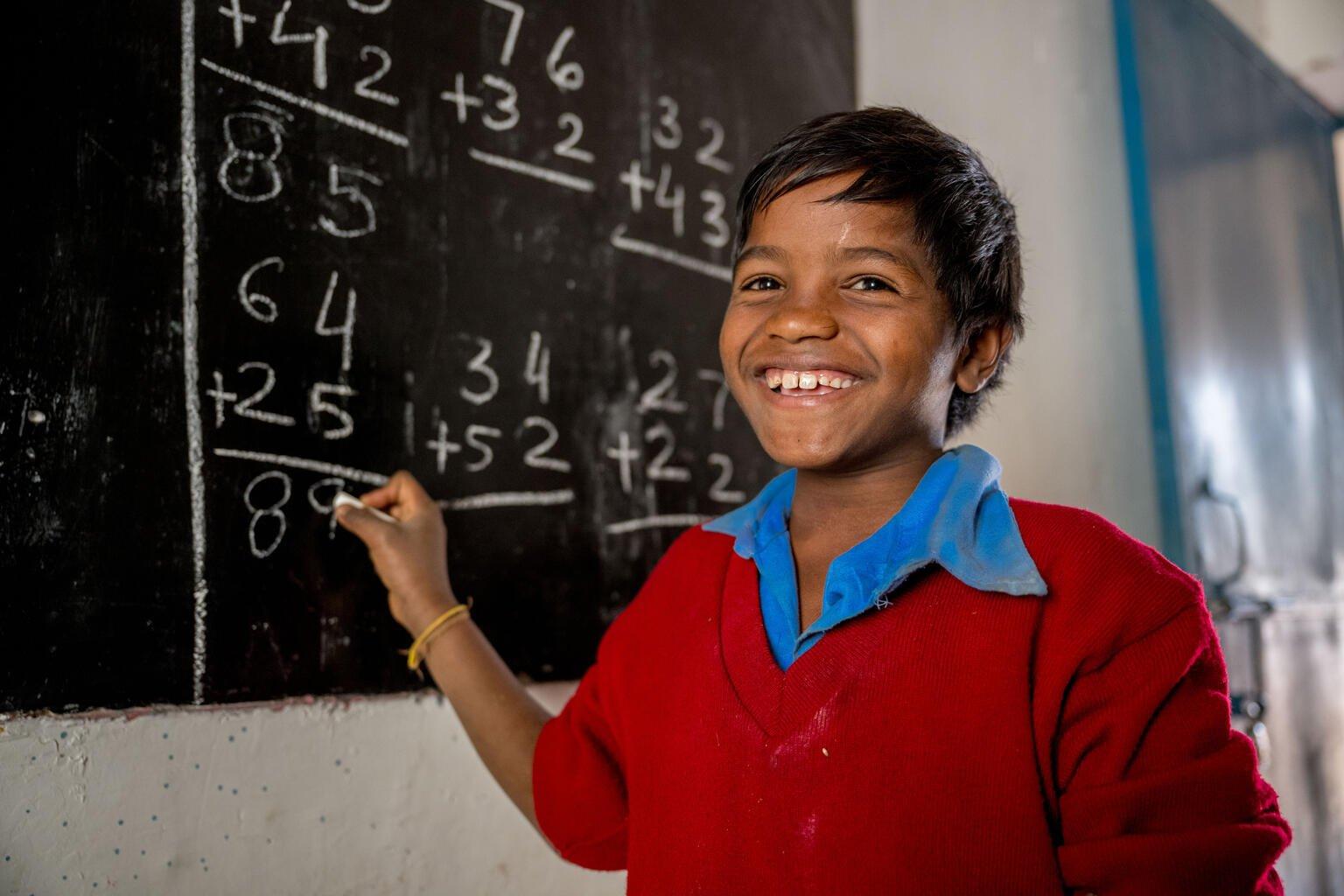 Jongen uit India doet een rekensom op het schoolbord