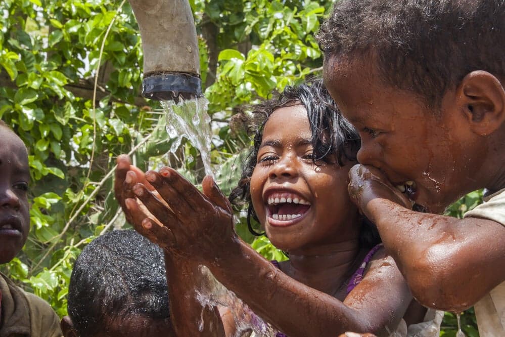 lachende kinderen bij waterkraan
