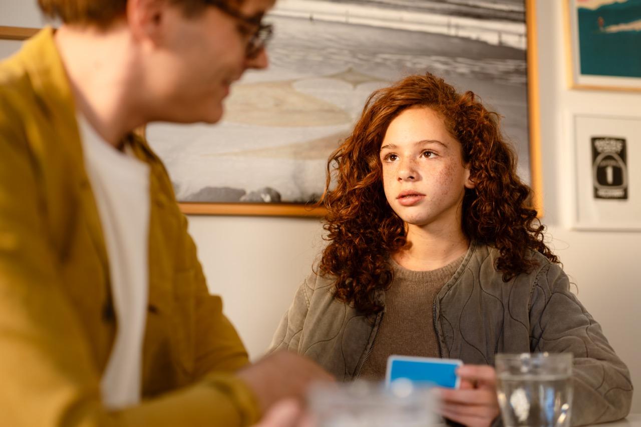meisje met rode krullen die een kaartspel in haar handen heeft