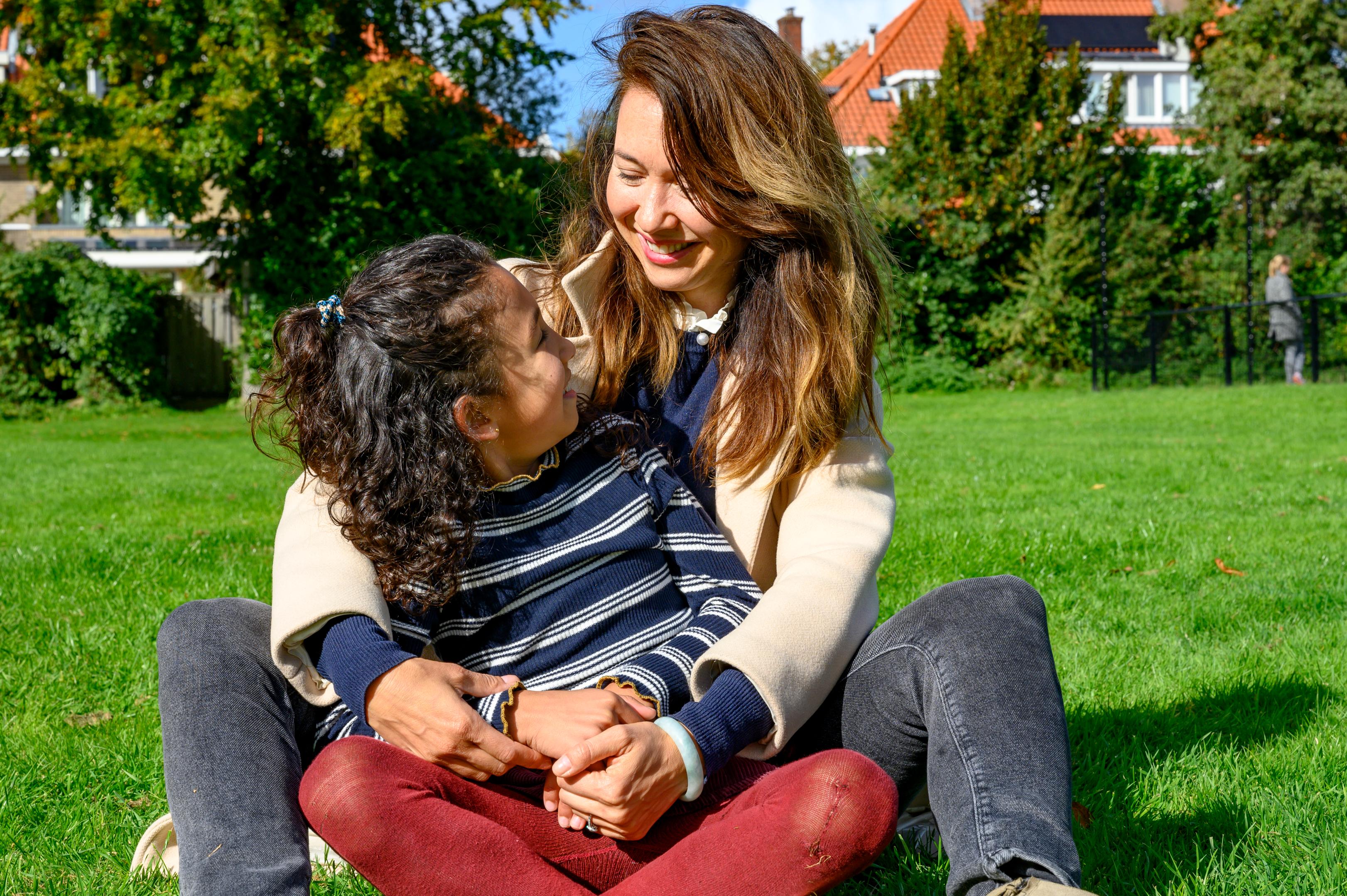 Moeder en dochter zitten samen in de zon in het gras