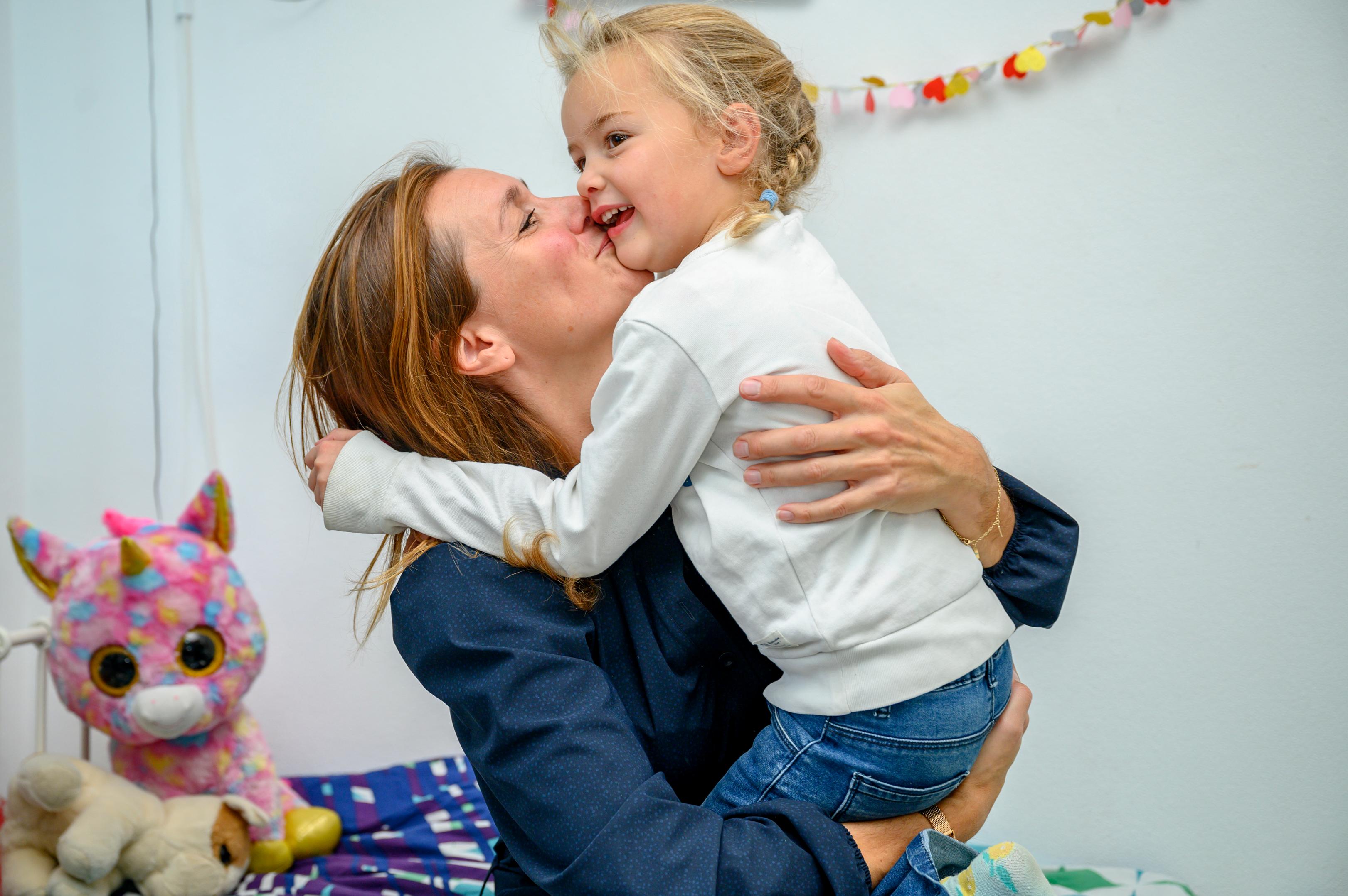 Moeder tilt haar dochter op en geeft haar blij een knuffel