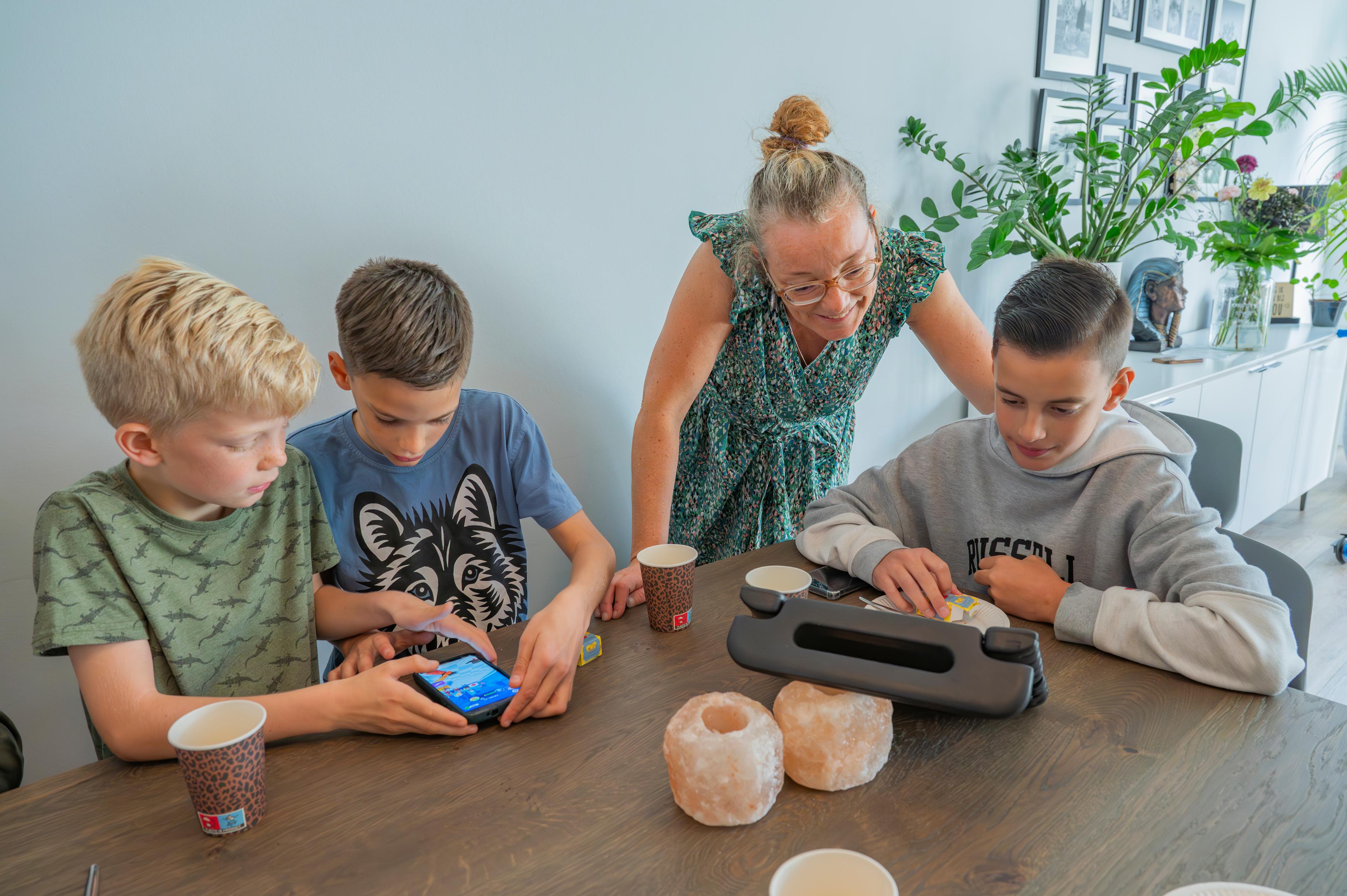 Moeder kijkt op de computer van drie jongens mee