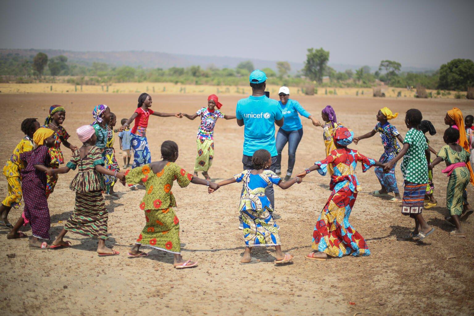 Kinderen dansen rondom een UNICEF medewerker