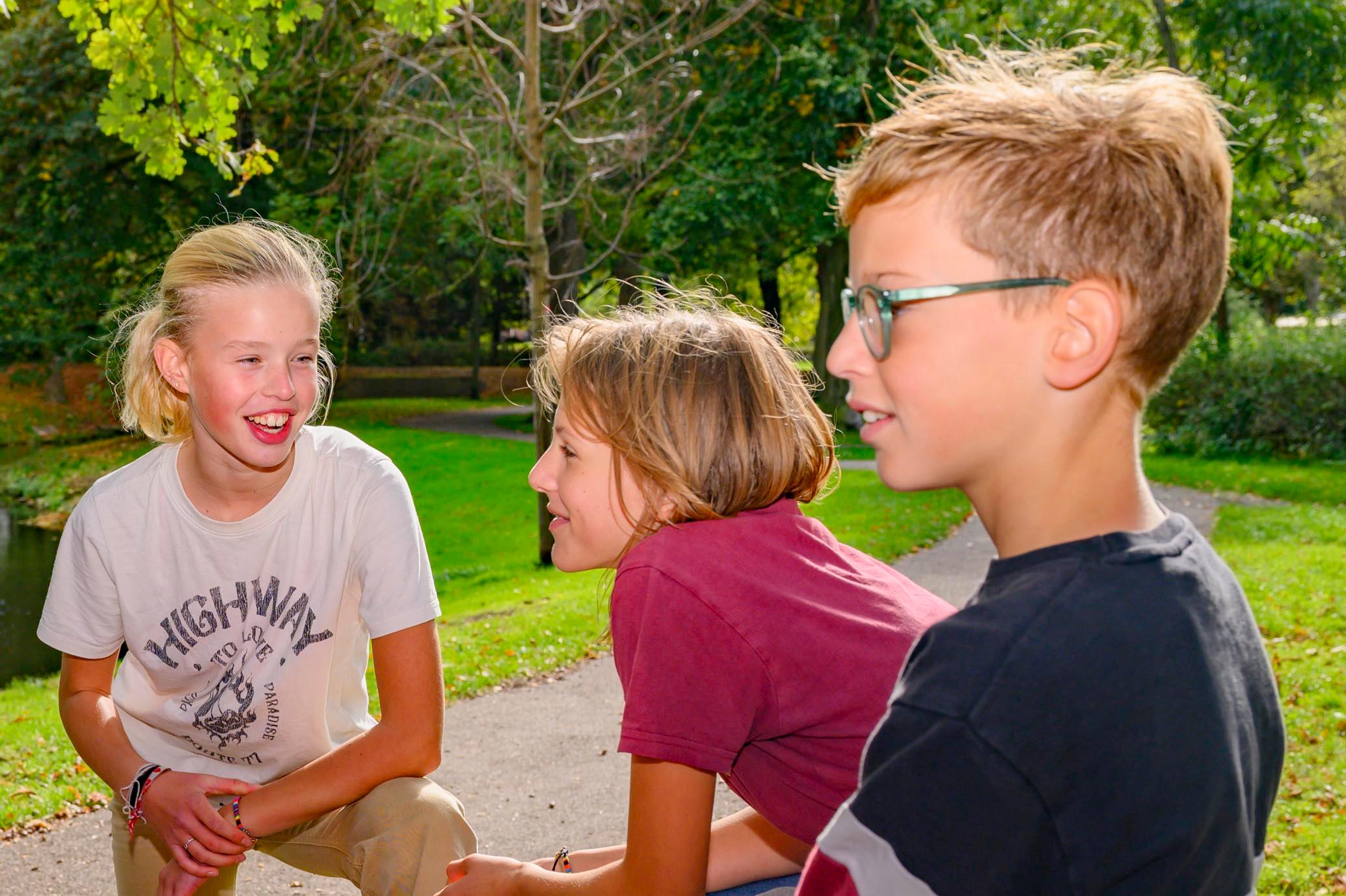 Jongeren kletsen en lachen op een bankje in bos