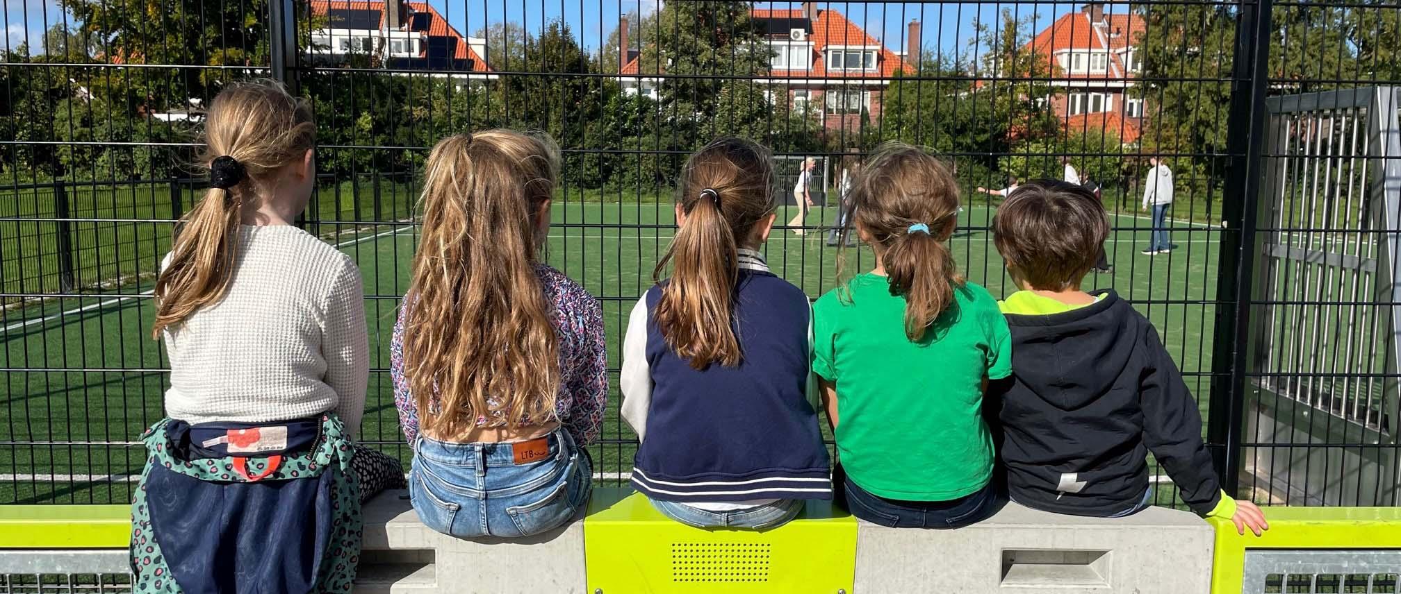 Kinderen op speelveld kijken naar sporters
