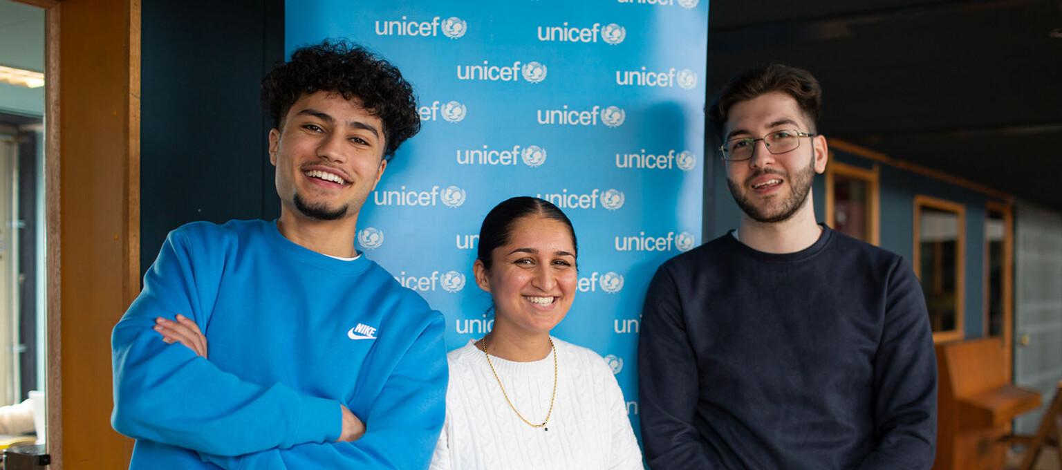 drie lachende jongeren bij unicef-logo