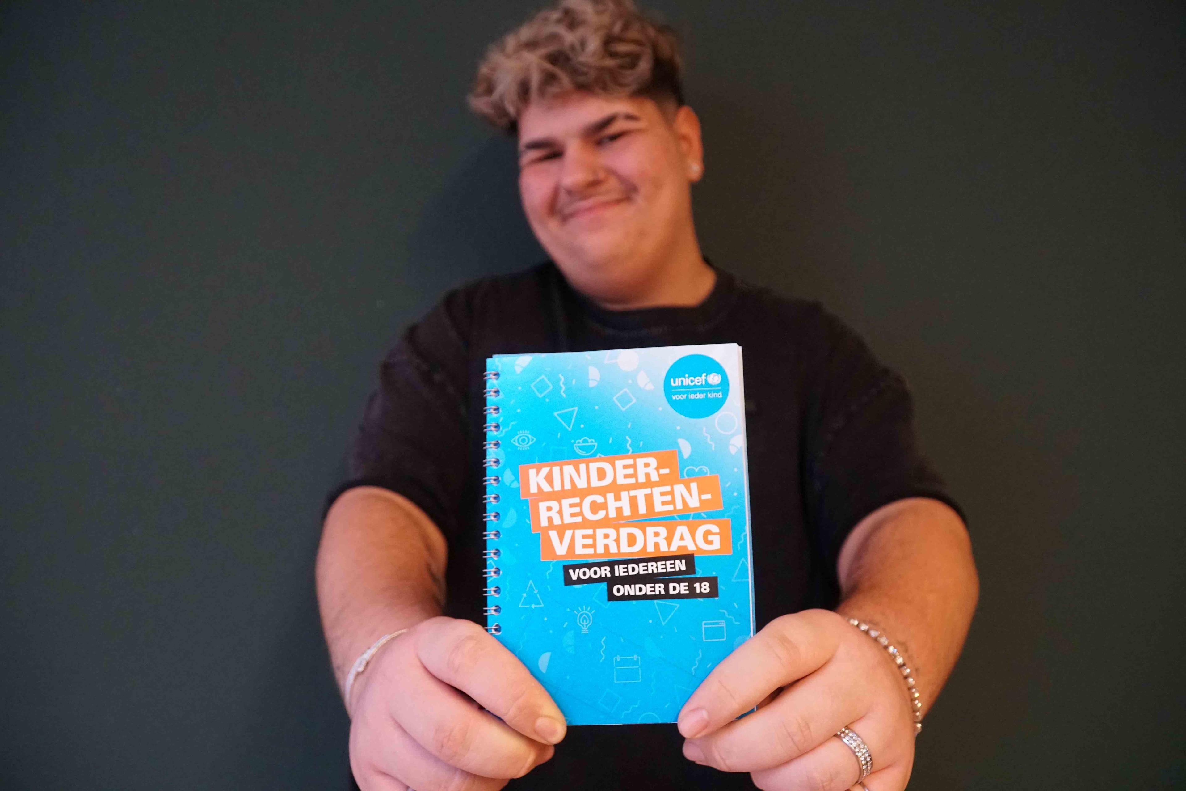 jongen houdt kinderrechtenverdragboekje naar de camera