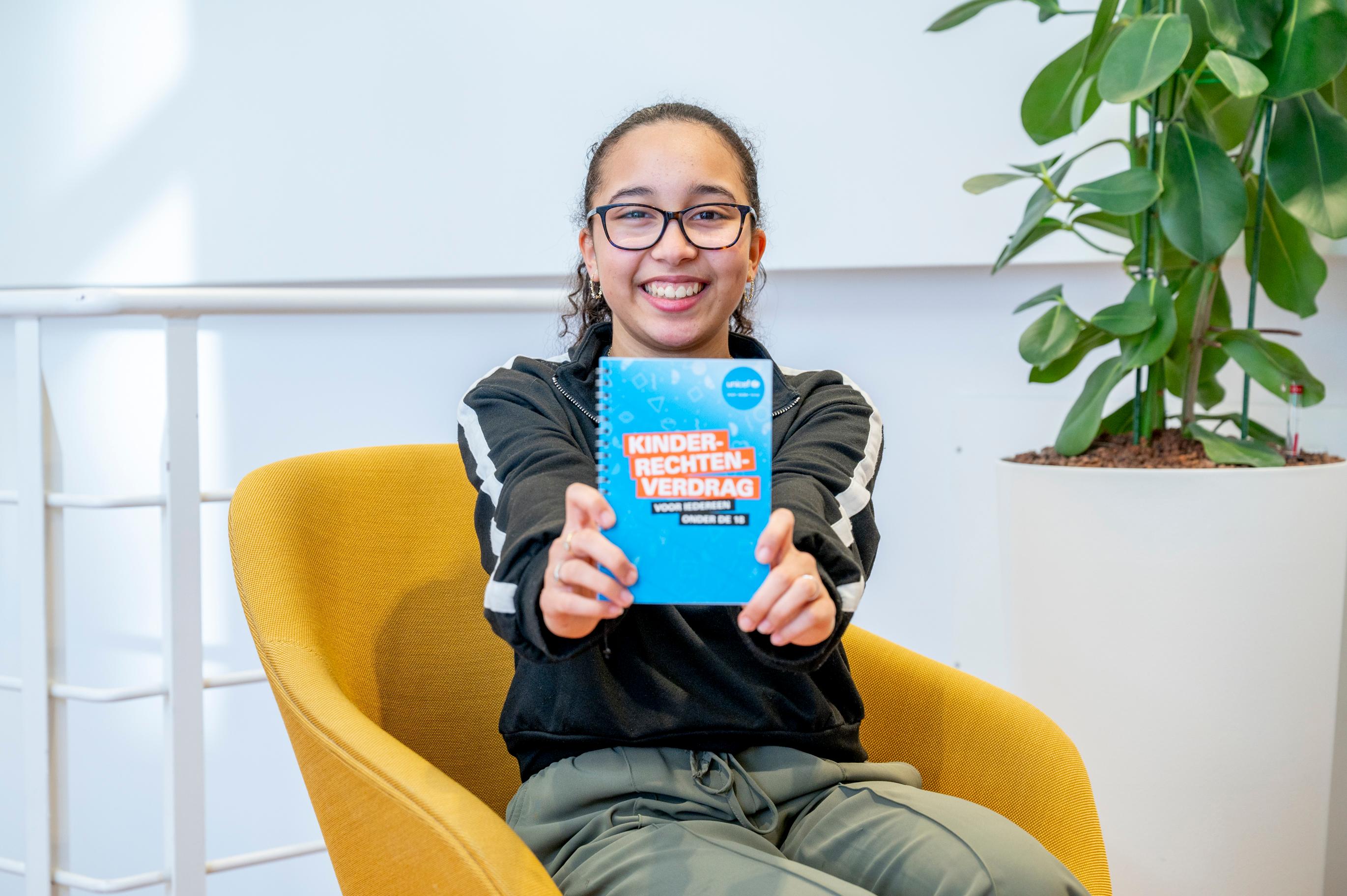 Een meisje houdt het Kinderrechtenboekje vast.