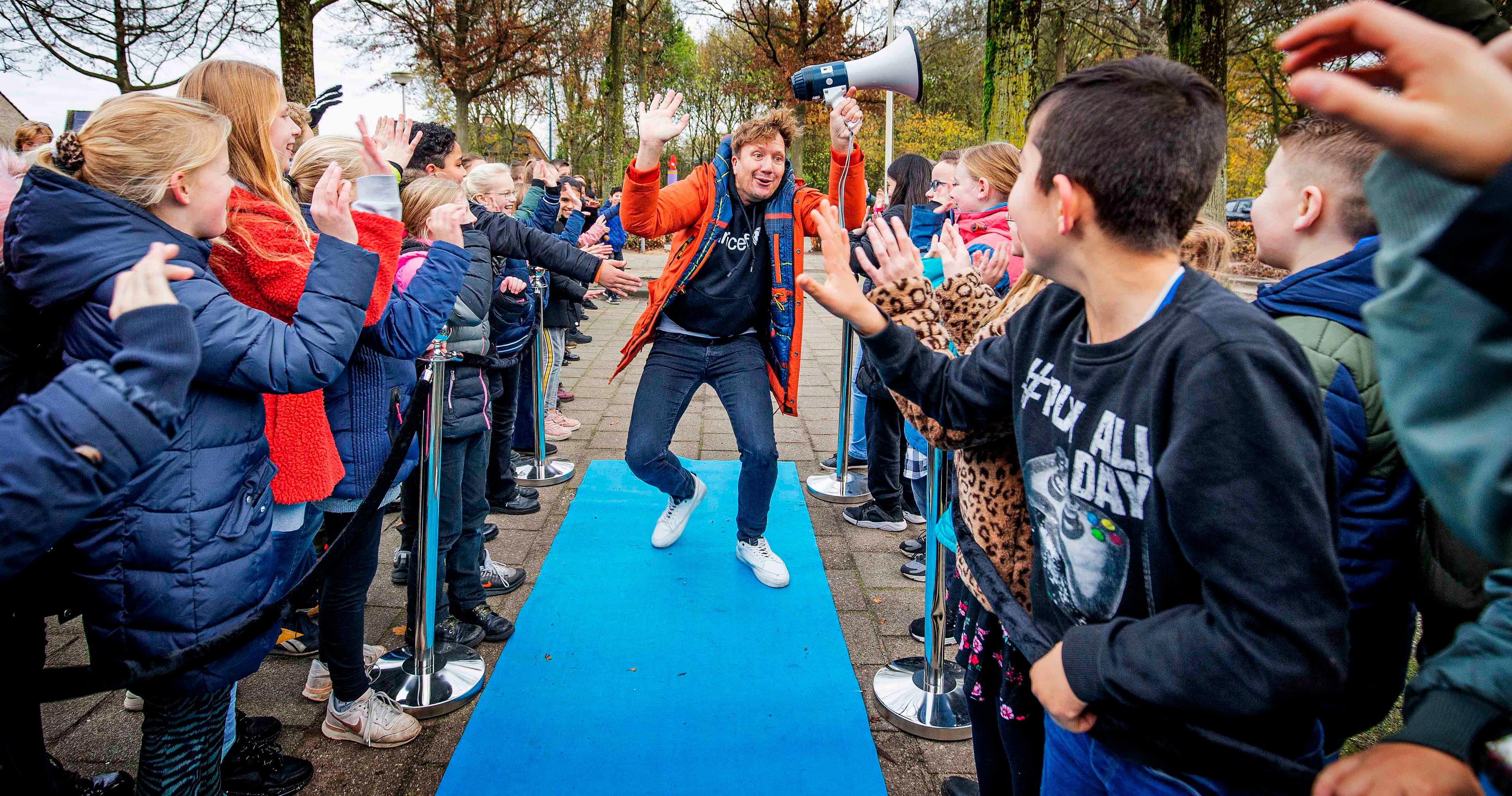 Klaas van Kruistem loopt over blauwe loper aangemoedigd door kinderen
