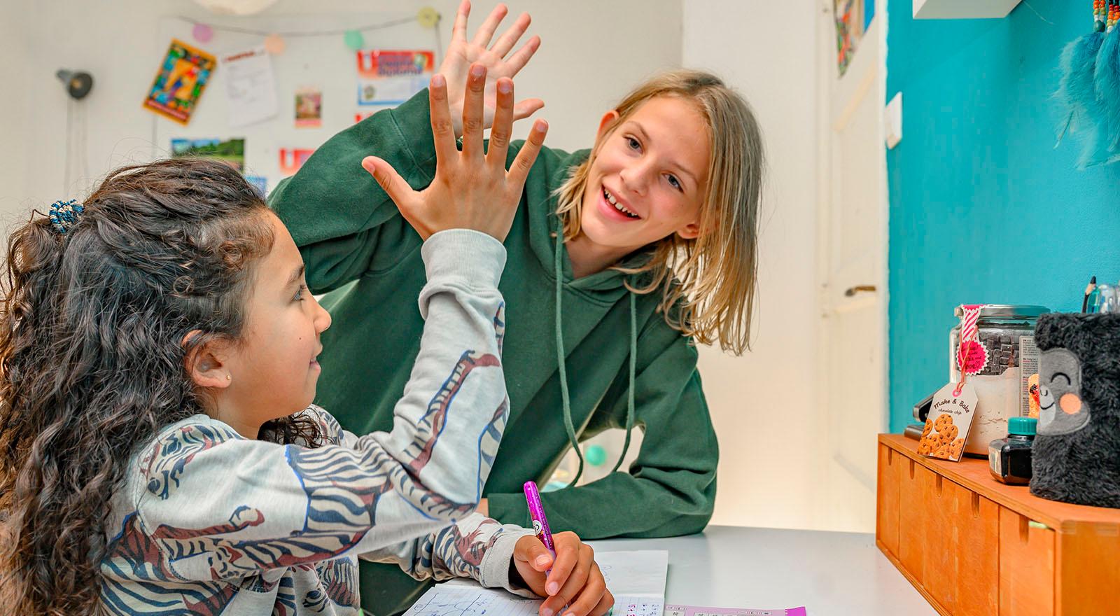meisjes geven elkaar highfive bij het huiswerk maken