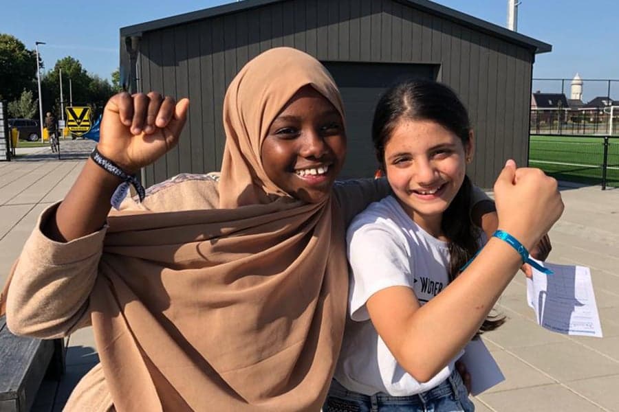 Twee meisjes bij de UNICEF Loop showen hun UNICEF-bandje.