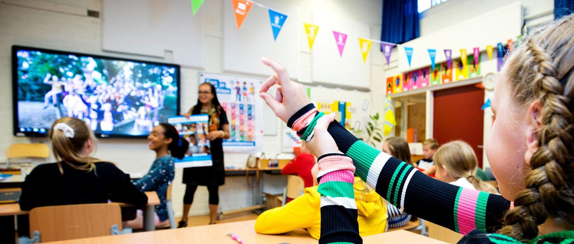 Meisje steekt hand op tijdens kinderrechtenles in de klas