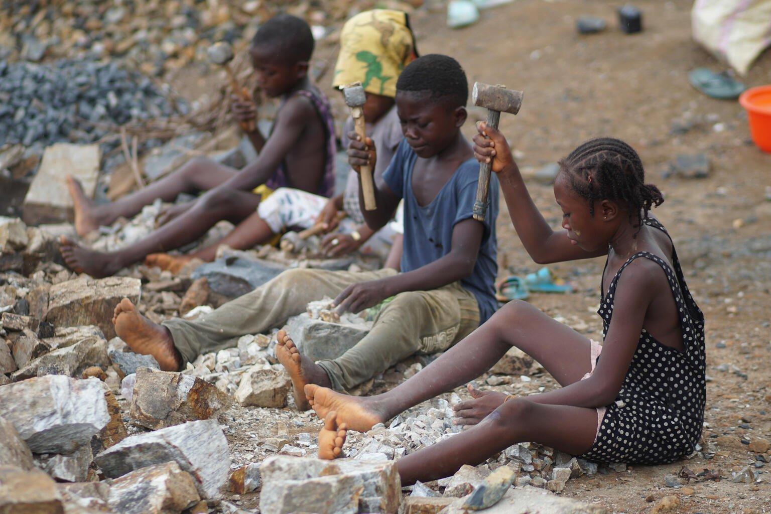 Kinderen in Kenema, Sierra Leone, breken grote stukken graniet tot grind om deze te verkopen aan aannemers.