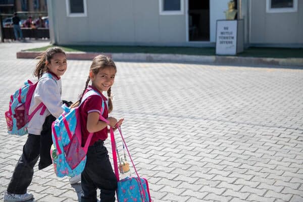 Twee meisjes lopen samen naar huis na school op het schoolplein van de UNICEF-basisschool in Pazarcık, Kahramanmaraş, Turkije.