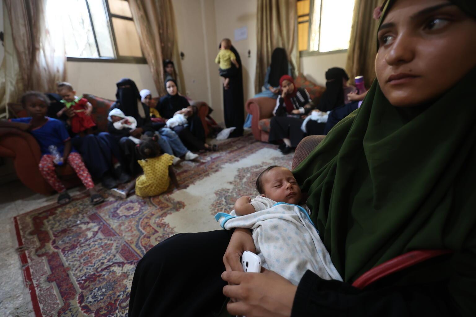 Moeder zit met baby op schoot bij voedselhulppunt in Gaza