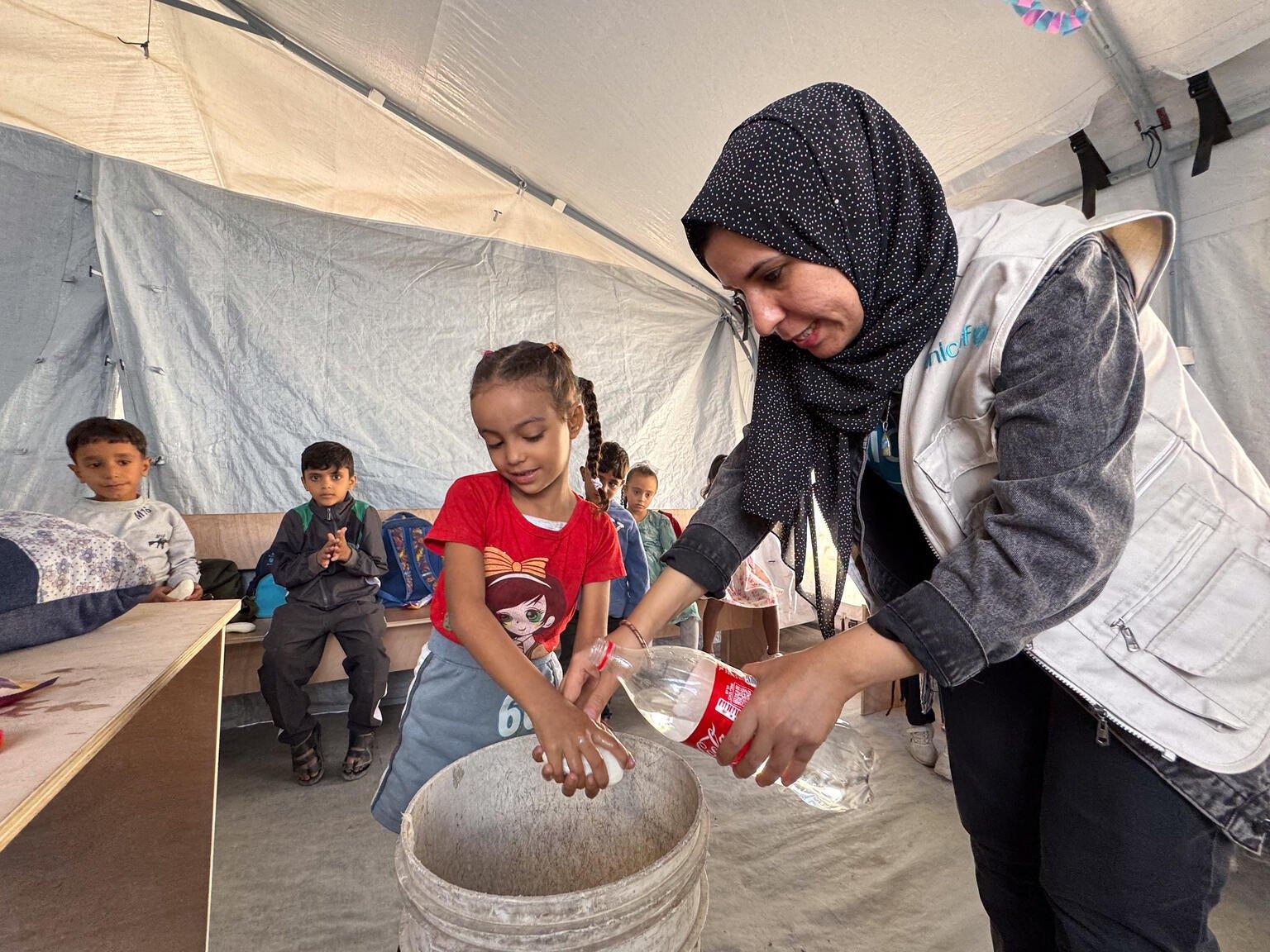 Meisje in Gaza krijgt les over hoe ze zeep goed moet gebruiken door een UNICEF medewerker. Ze kijken allebei naar de wasbak.