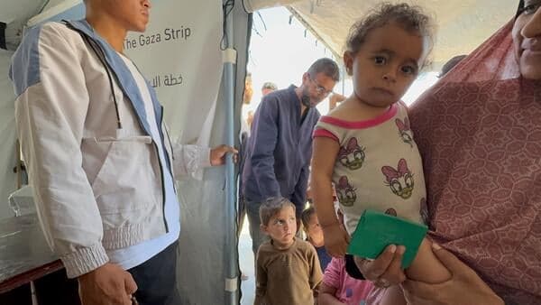 Mensen met jonge kinderen komen de door UNICEF ondersteunde voedingskliniek binnen, waar kinderen worden gescreend op ondervoeding