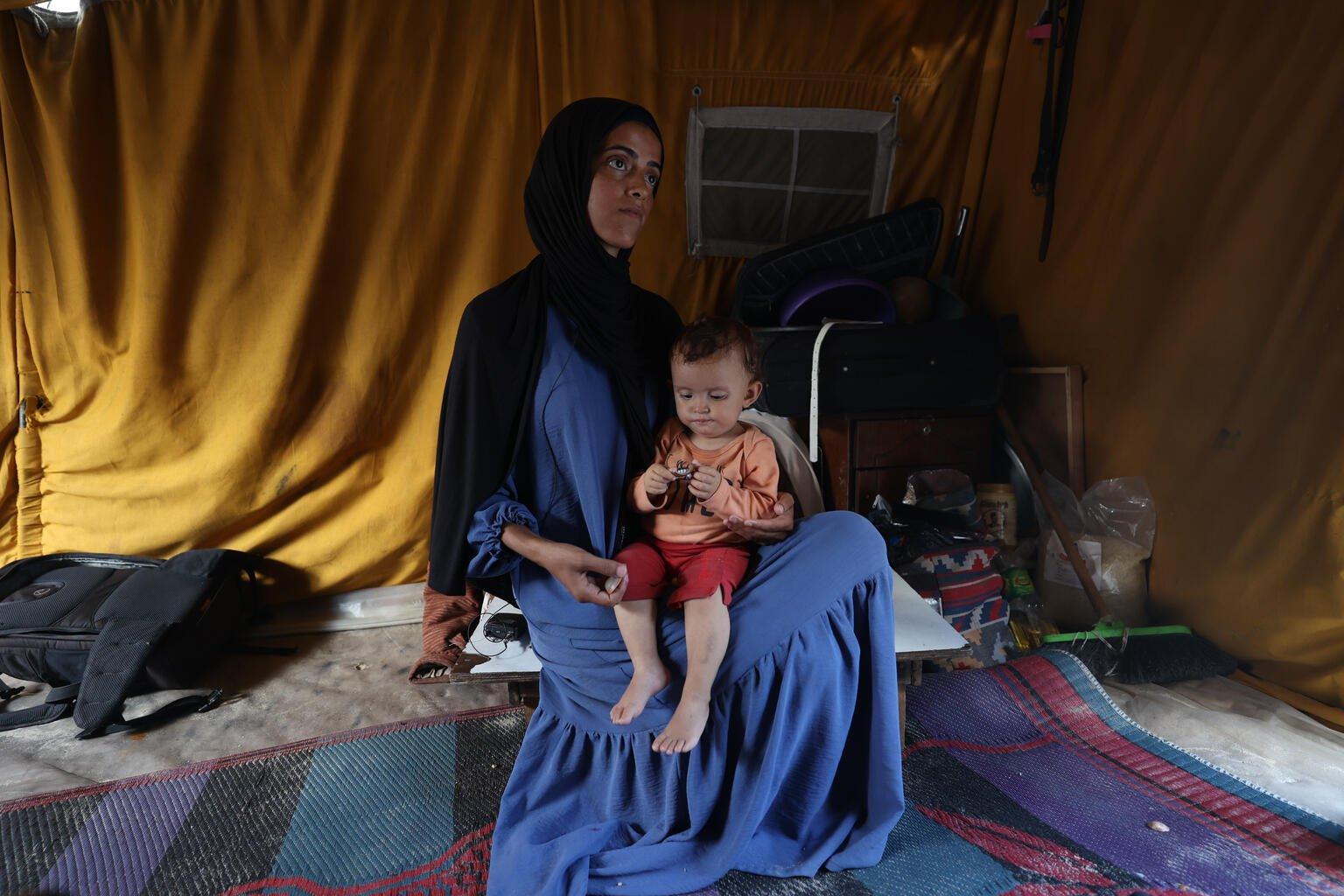 Een dochtertje op schoot bij haar moeder in Al-Mawasi in Gaza.