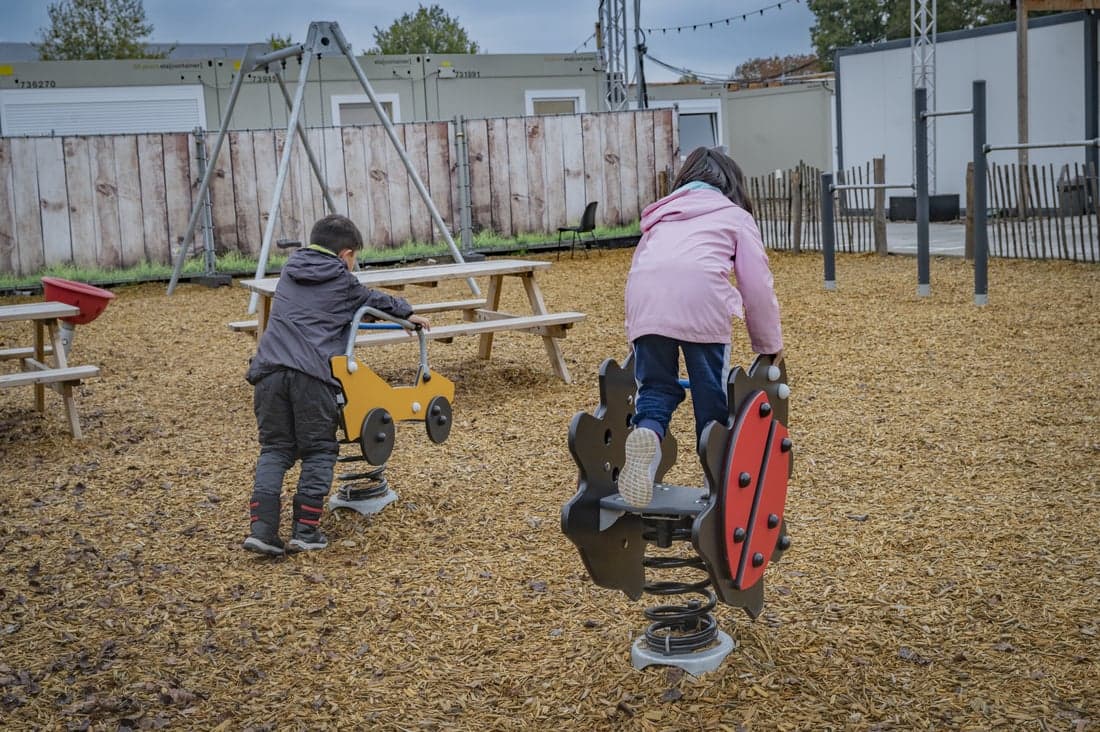 twee kinderen in speeltuin met rug naar de camera in een asielnoodopvang in Dongen