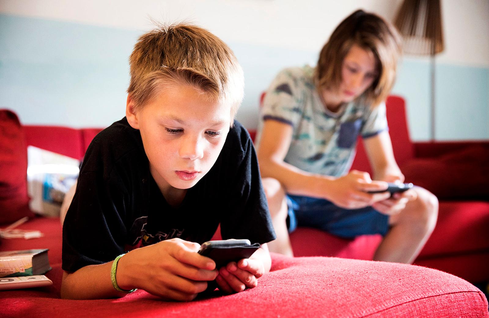 Nederlandse jongeren zitten op de bank op hun telefoon.