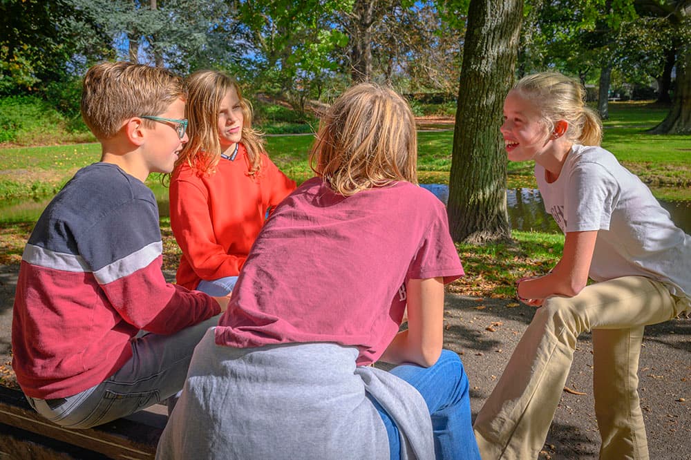 Jongeren op een bankje in een bos.