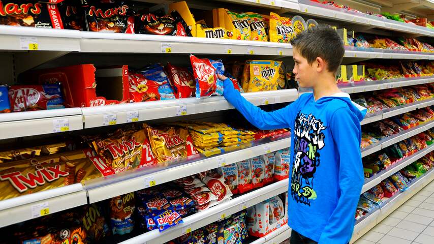 jongetje dat voor de ongezonde spullen staat in de supermarkt