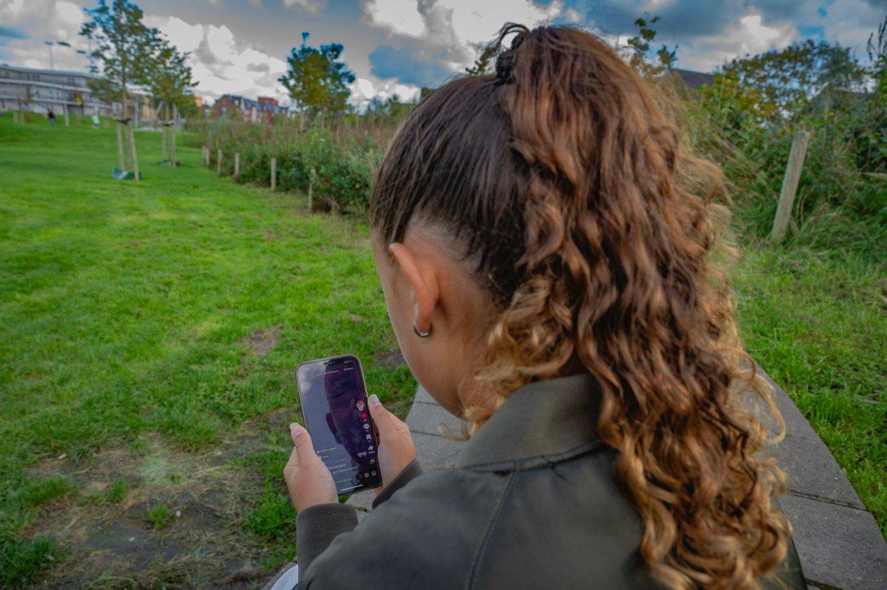Tiener meisje op de rug gefotografeerd kijkt naar mobiele telefoon