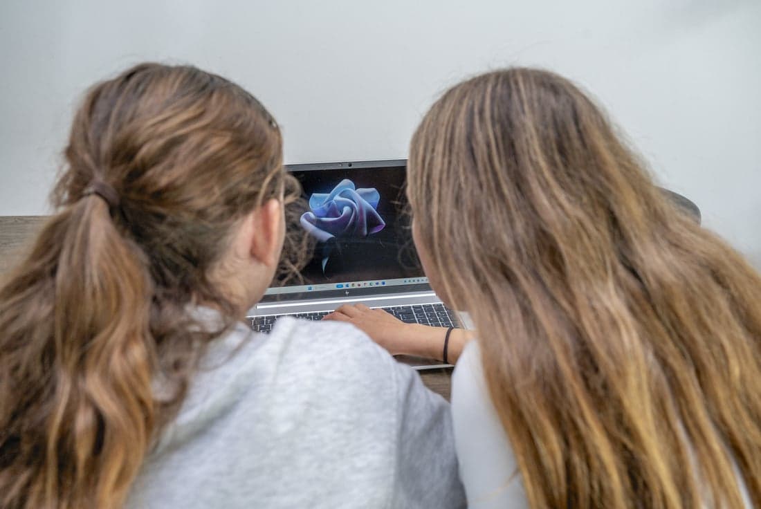 Twee meisjes zitten achter een laptop
