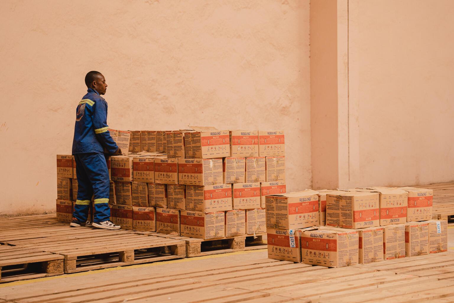 Man stapelt dozen met noodhulp goederen af voor doorlevering