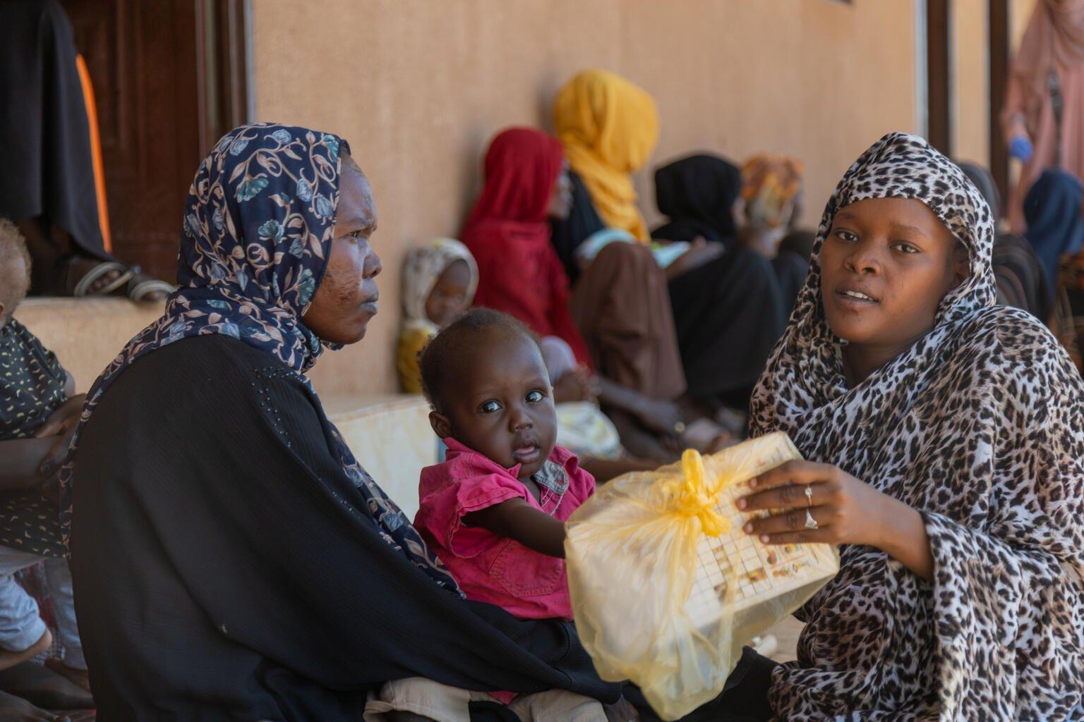 Gezondheidsmedewerker deelt pakket uit aan moeder en dochter voor cholera preventie