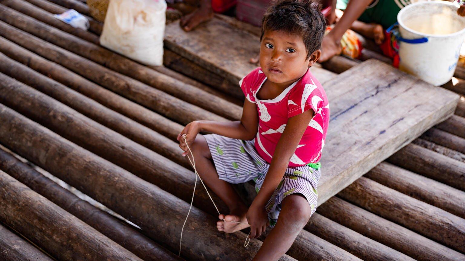 Een jongetje in Venezuela zit op de grond in een tijdelijke leerruimte.