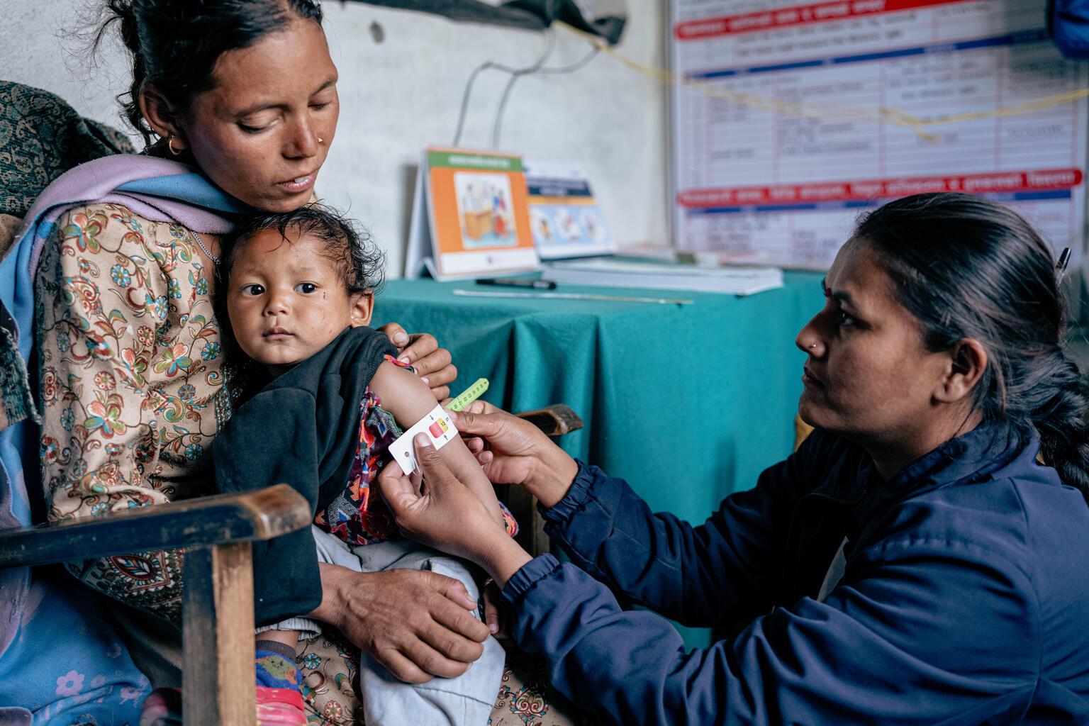 De arm van een meisje word opgemeten in Nepal voor de gezondheid