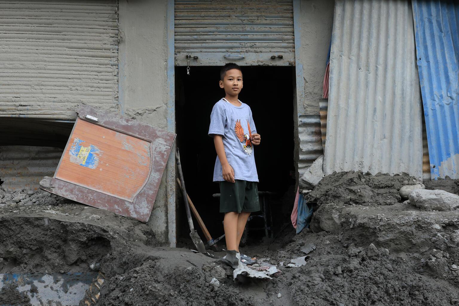 Jongen die voor een verwoest huis staat in Nepal