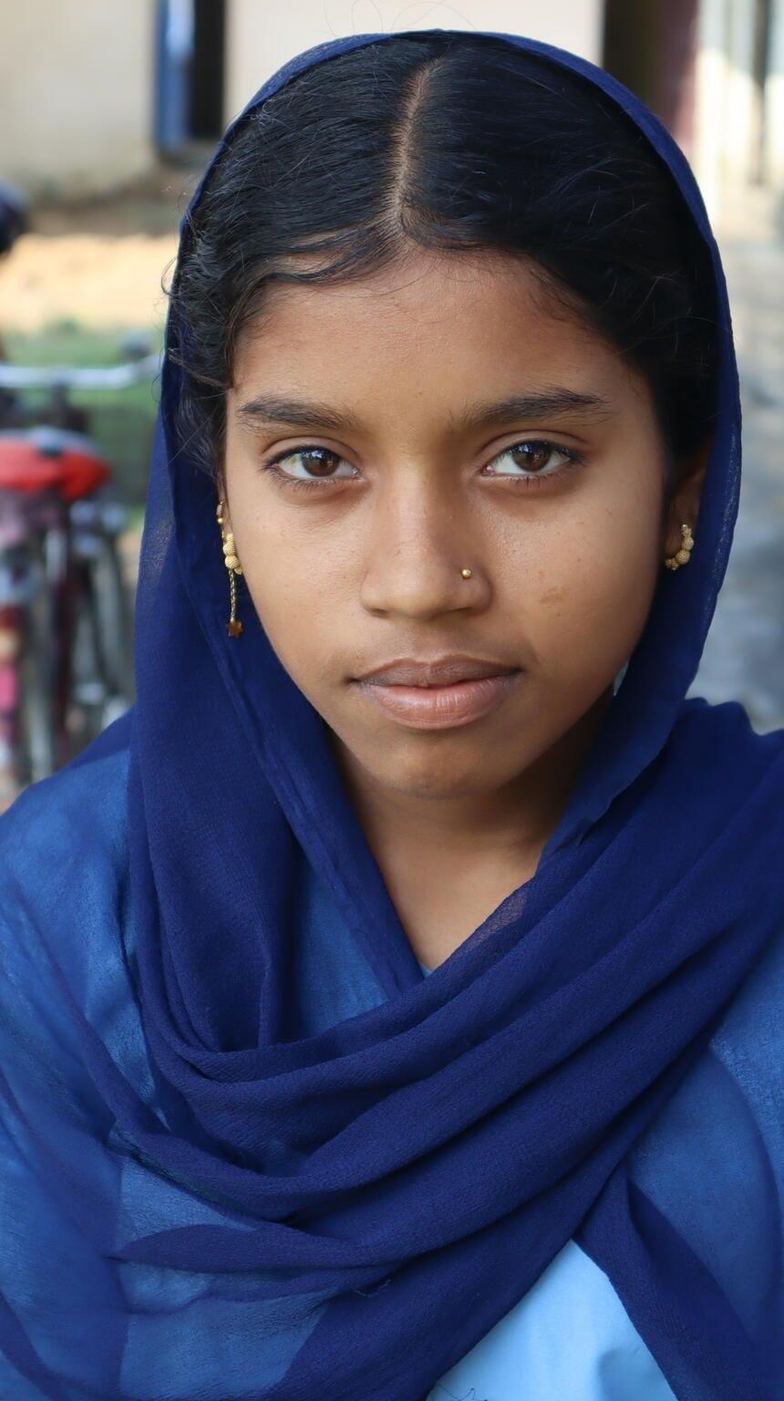 Meisje in Nepal met een blauw hoofddoek kijkend in de camera