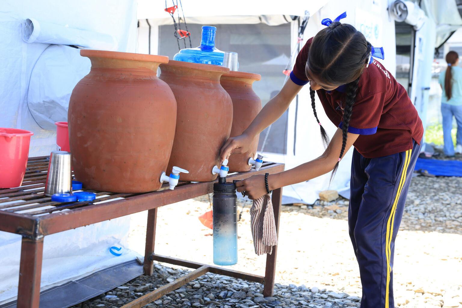 Meisje tapt drinkwater in een blauwe fles