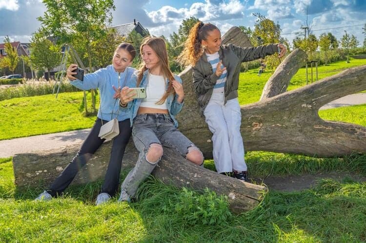meisjes met mobieltjes maken selfies in park