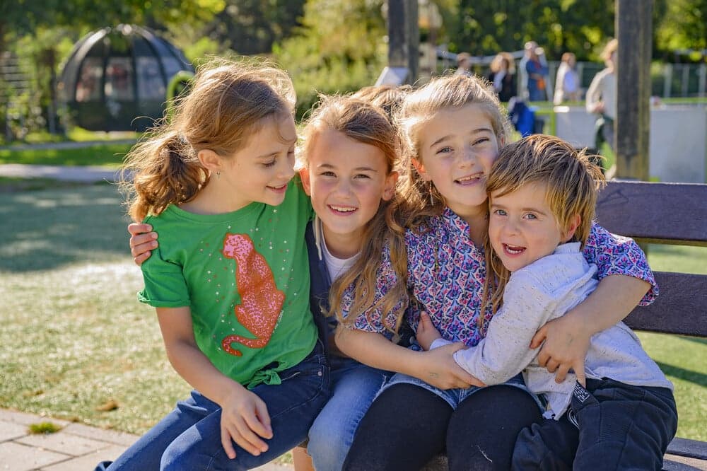 vier kinderen op een bankje in de zon