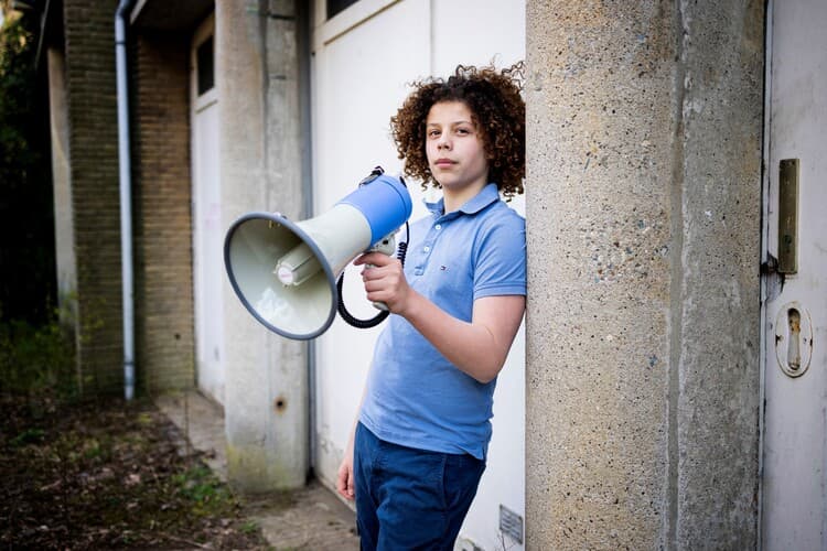 jongen met megafoon bij deur