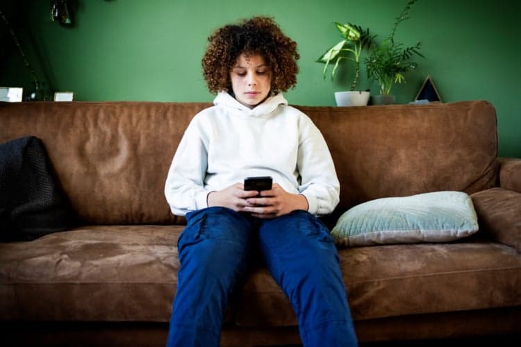jongen met mobieltje op bank