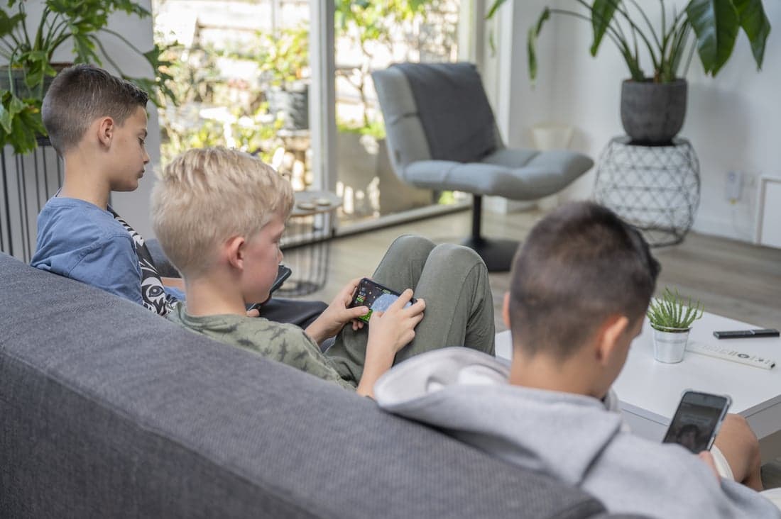 Jongens zitten op hun mobiel.