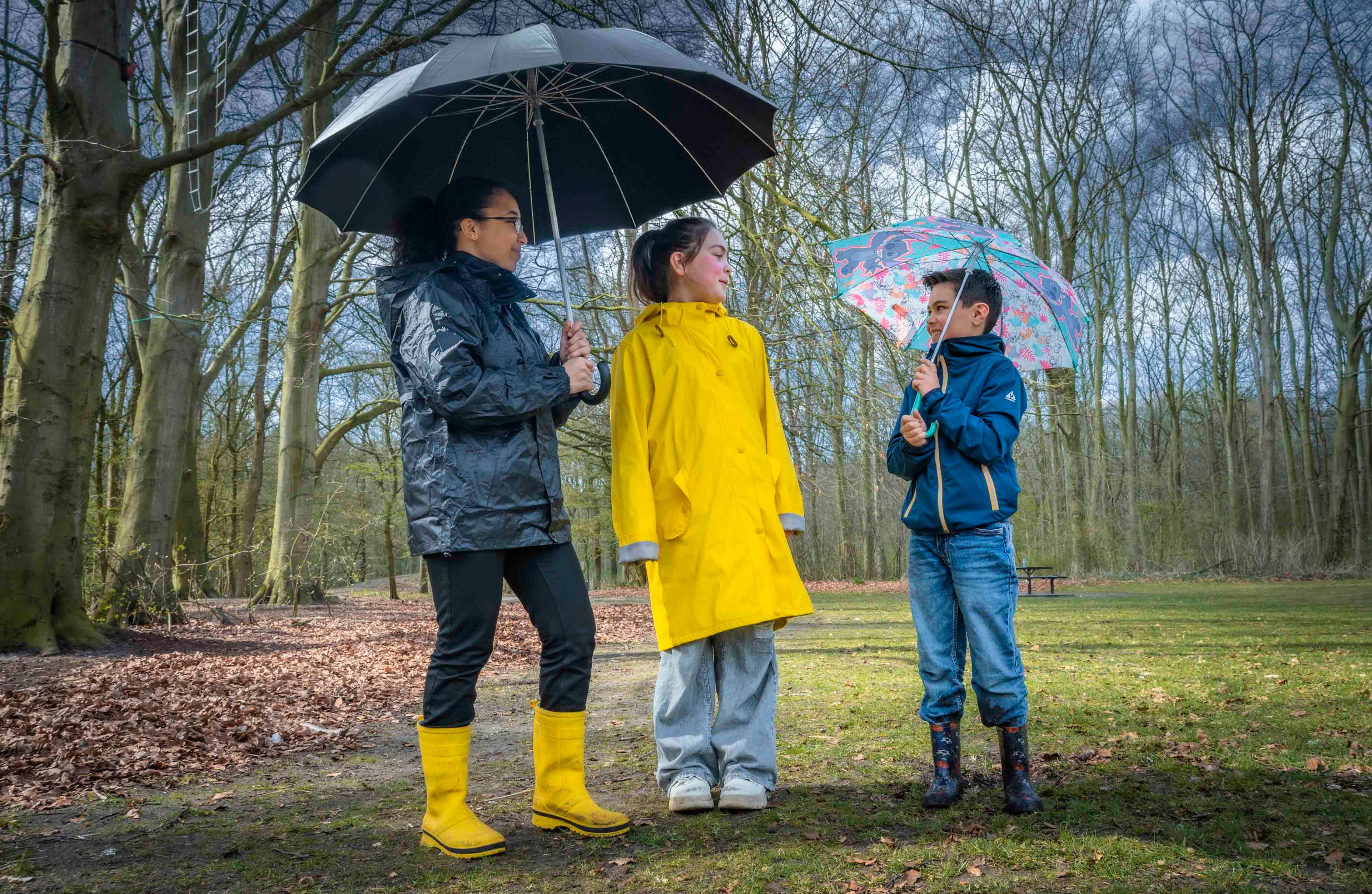 drie kinderen in bos met paraplu