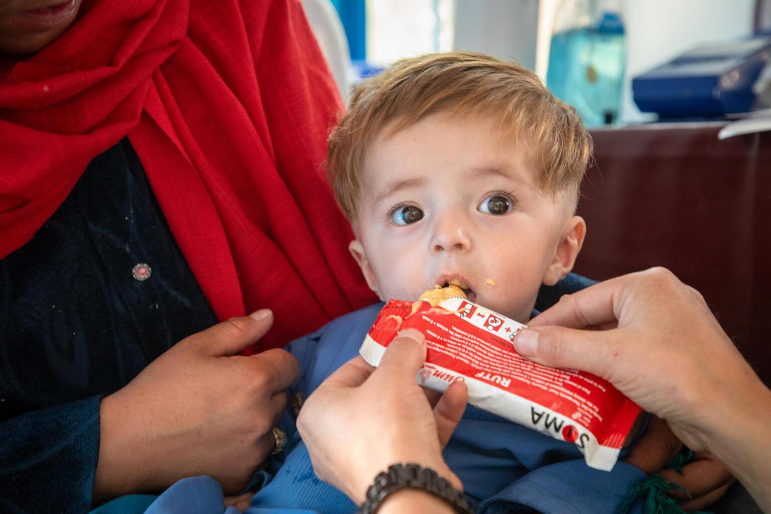 9 maanden oude peuter, jongen, krijgt een zakje plumpy nut om aan te sterken